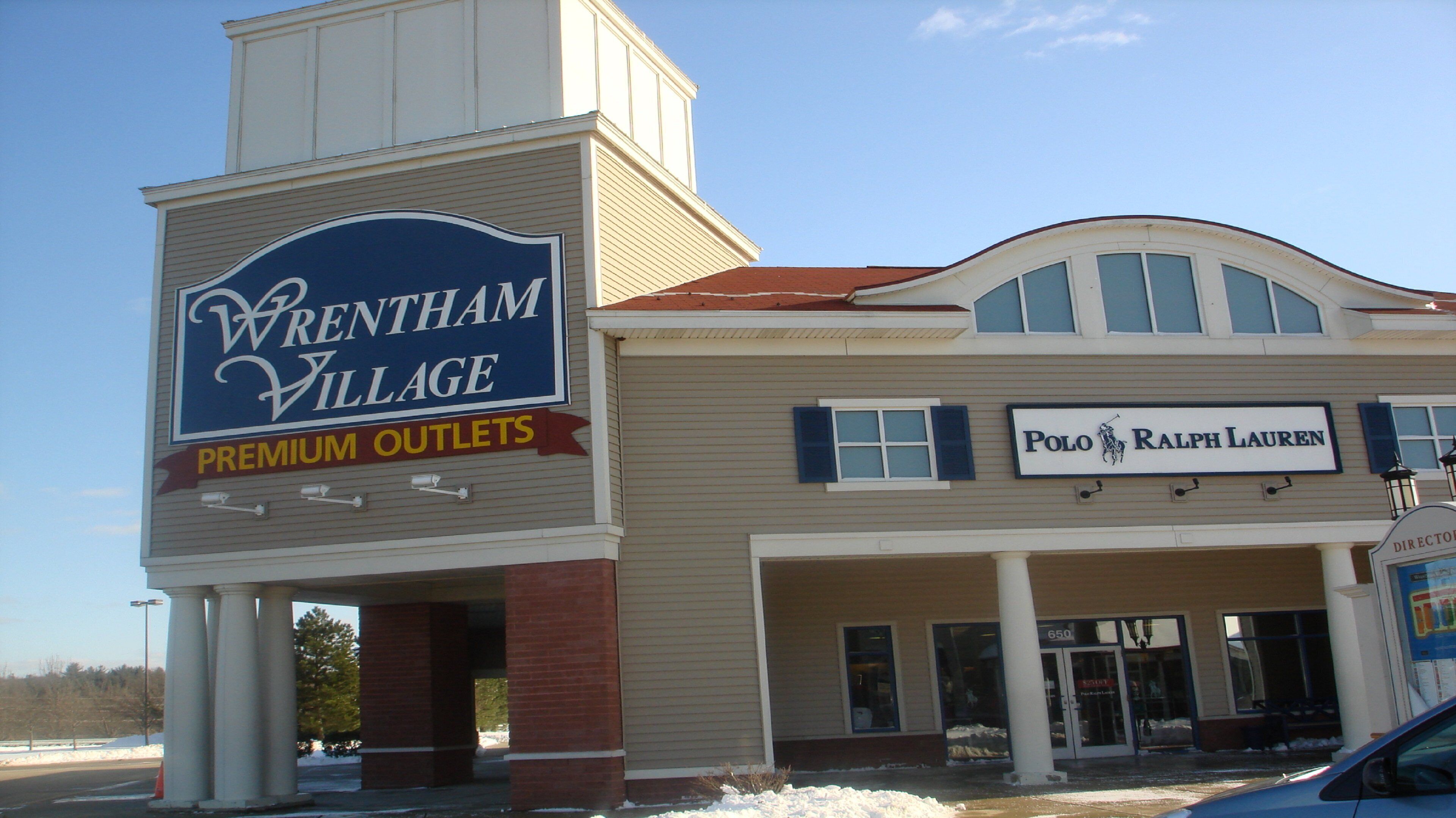 A building with a sign for Wrenham Village Premium Outlets and a Polo Ralph Lauren store.