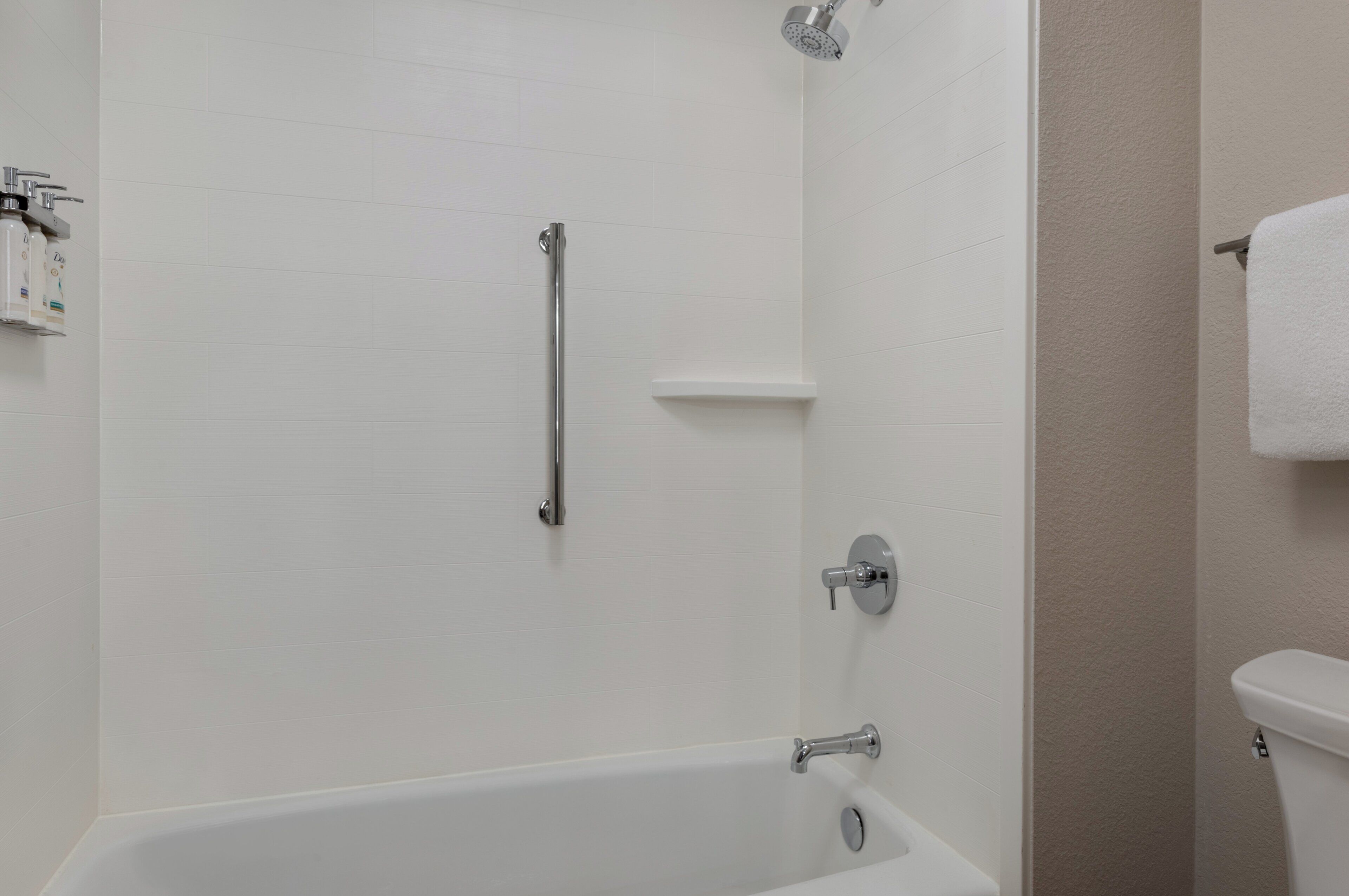 A bathroom with a white bathtub, a shower with a handheld showerhead, and a toilet.