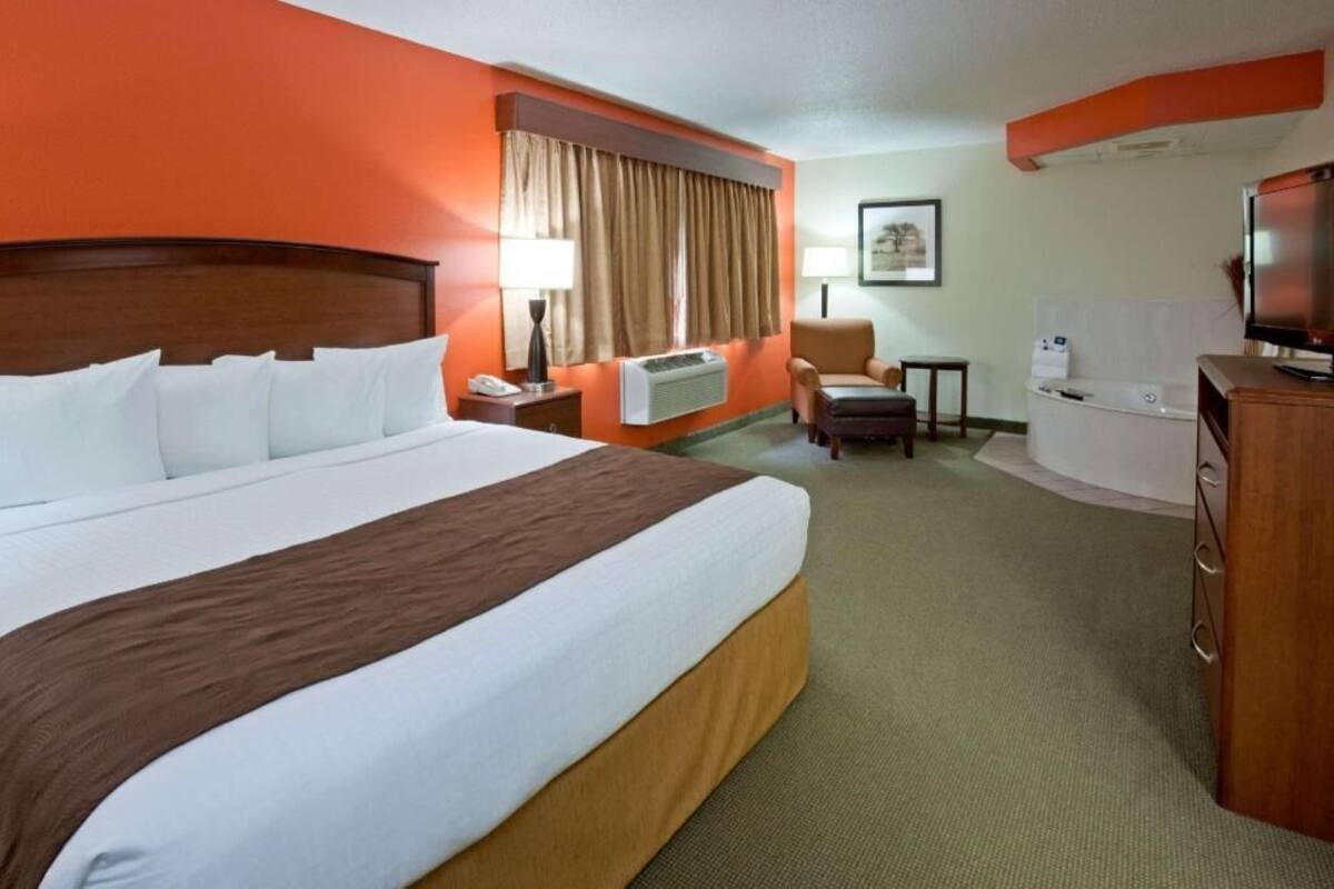 Une chambre d’hôtel avec un grand lit, un bureau, une chaise, une télévision et une petite table.