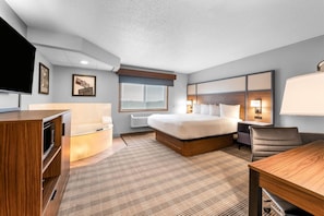 Una habitación de hotel con cama, mesita de noche, lámpara y escritorio con silla.