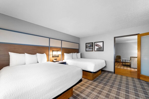 A hotel room with two beds, a wooden headboard, a nightstand, a lamp, and a framed picture on the wall. - AmericInn by Wyndham Sauk Centre (Sauk Centre)