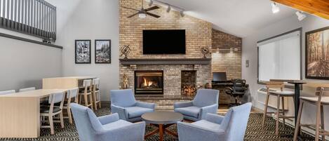 A modern living room with a fireplace, seating area, and a flat-screen TV mounted on the wall.