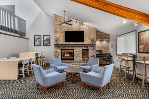 A modern living room with a fireplace, seating area, and a flat-screen TV mounted on the wall.