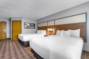 Une chambre d’hôtel avec deux lits, une porte en bois, une lampe fixée au mur et un comptoir d’enregistrement.