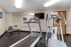 Une salle de remise en forme équipée d’un tapis de course, d’un vélo elliptique et d’haltères.