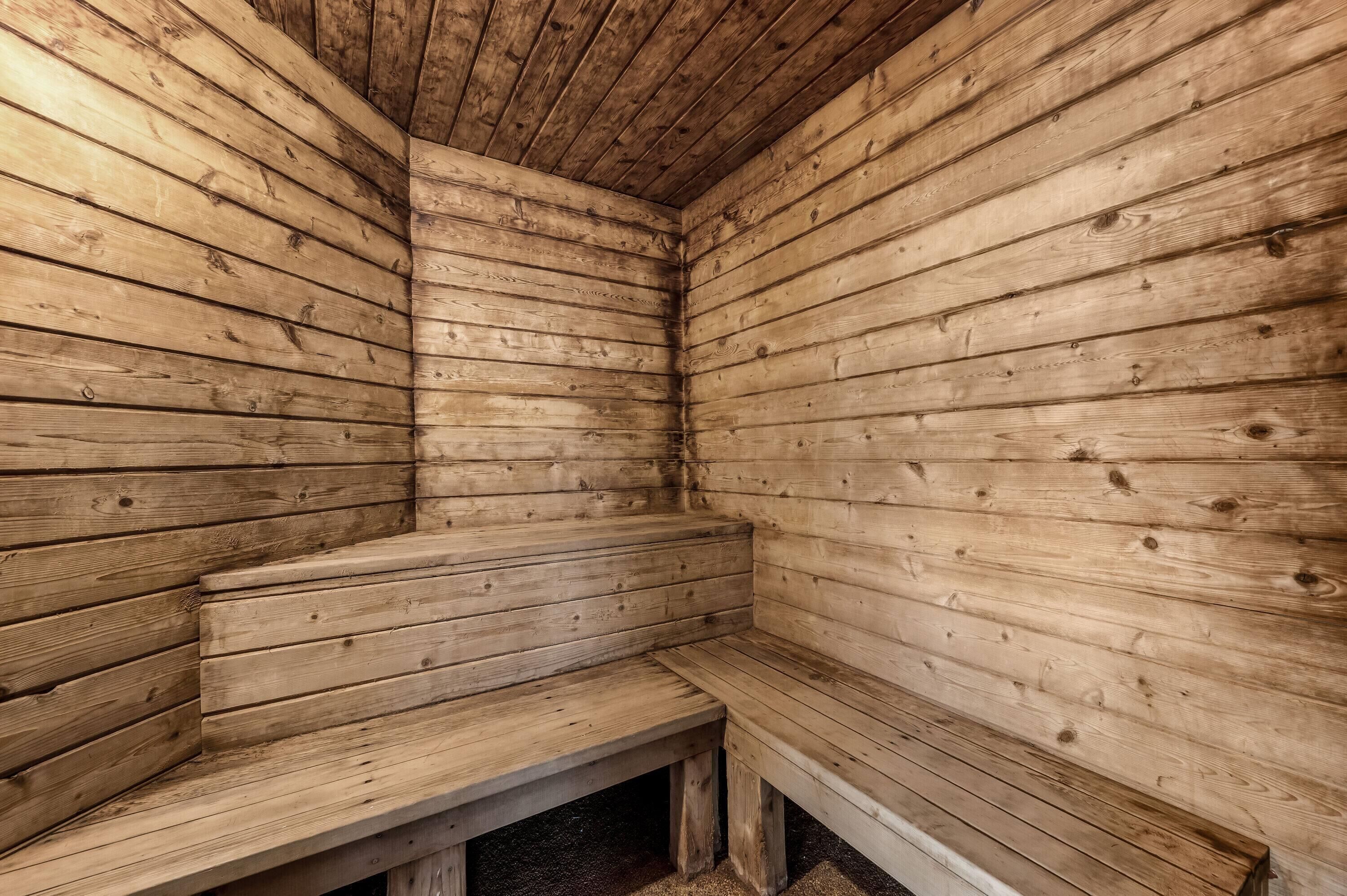 A wooden sauna with benches and a sloped ceiling.