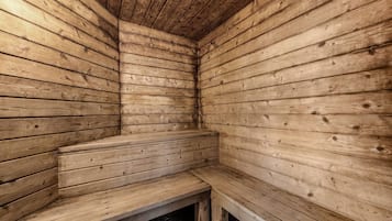 A wooden sauna with benches and a sloped ceiling.