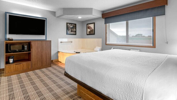 A hotel room with a large bed, a flat-screen TV, a microwave, and a small kitchenette. - AmericInn by Wyndham Sauk Centre (Sauk Centre)