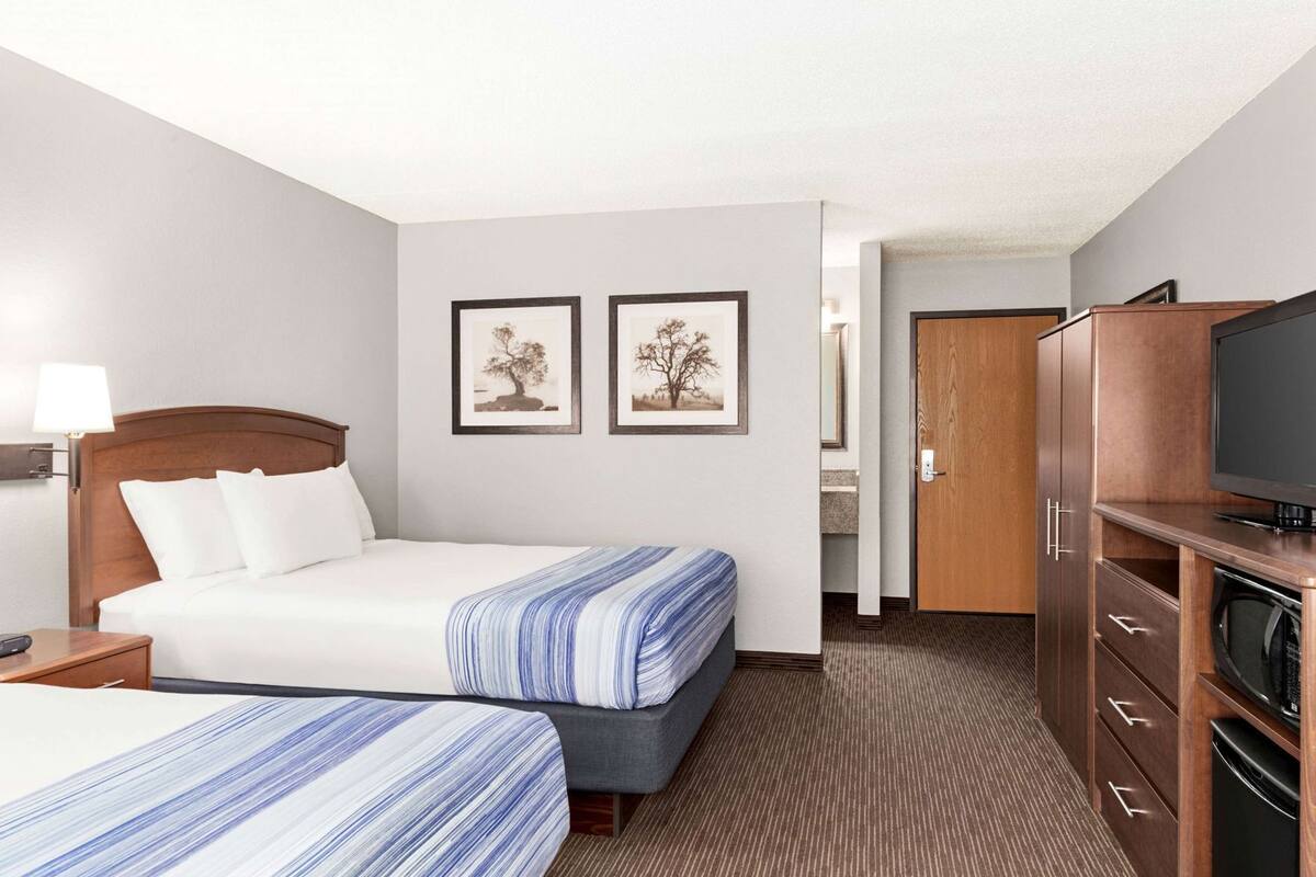 A hotel room with two beds, a TV, a desk, and a wardrobe.