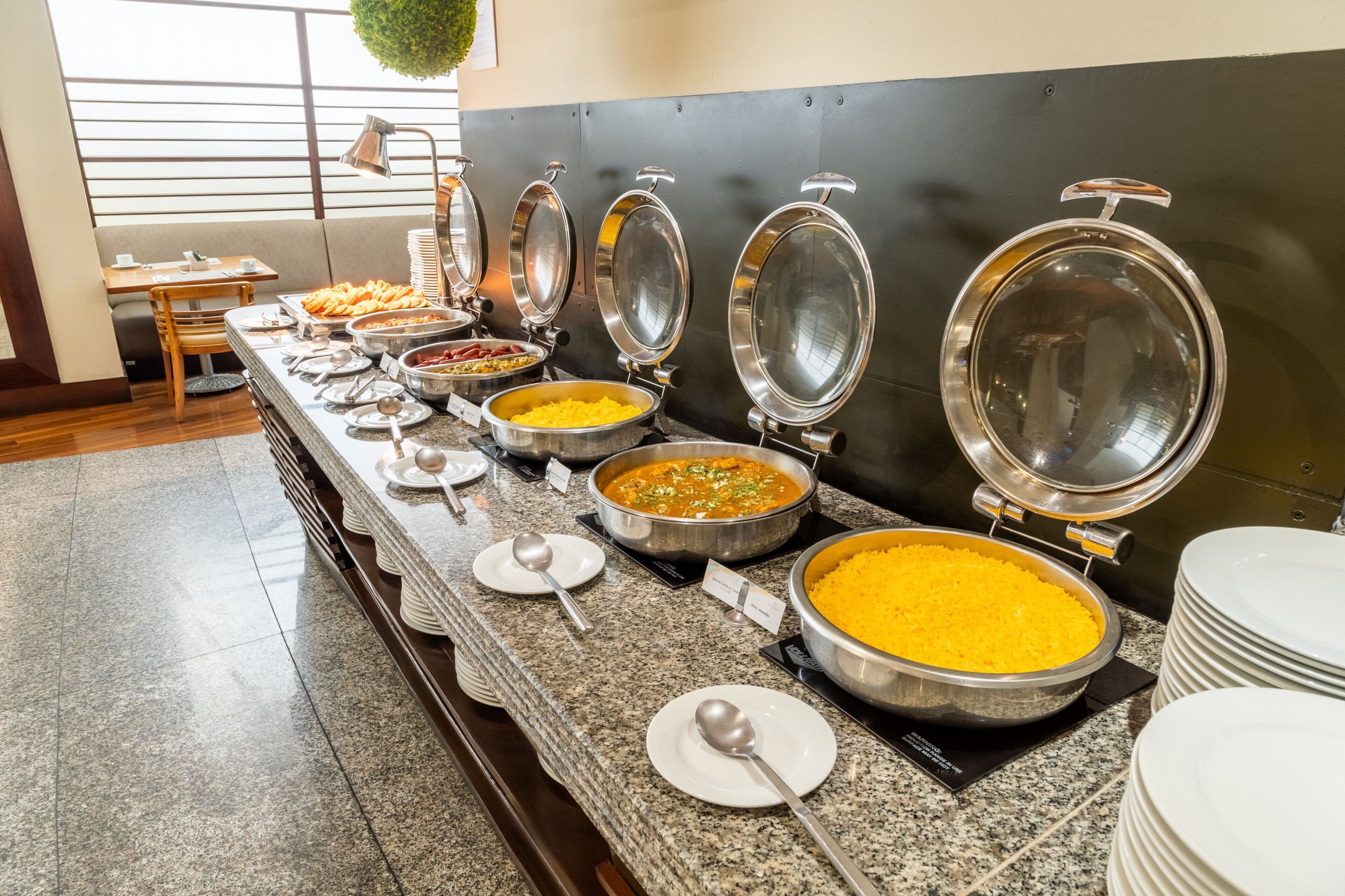 A buffet setup with various food items and serving utensils.