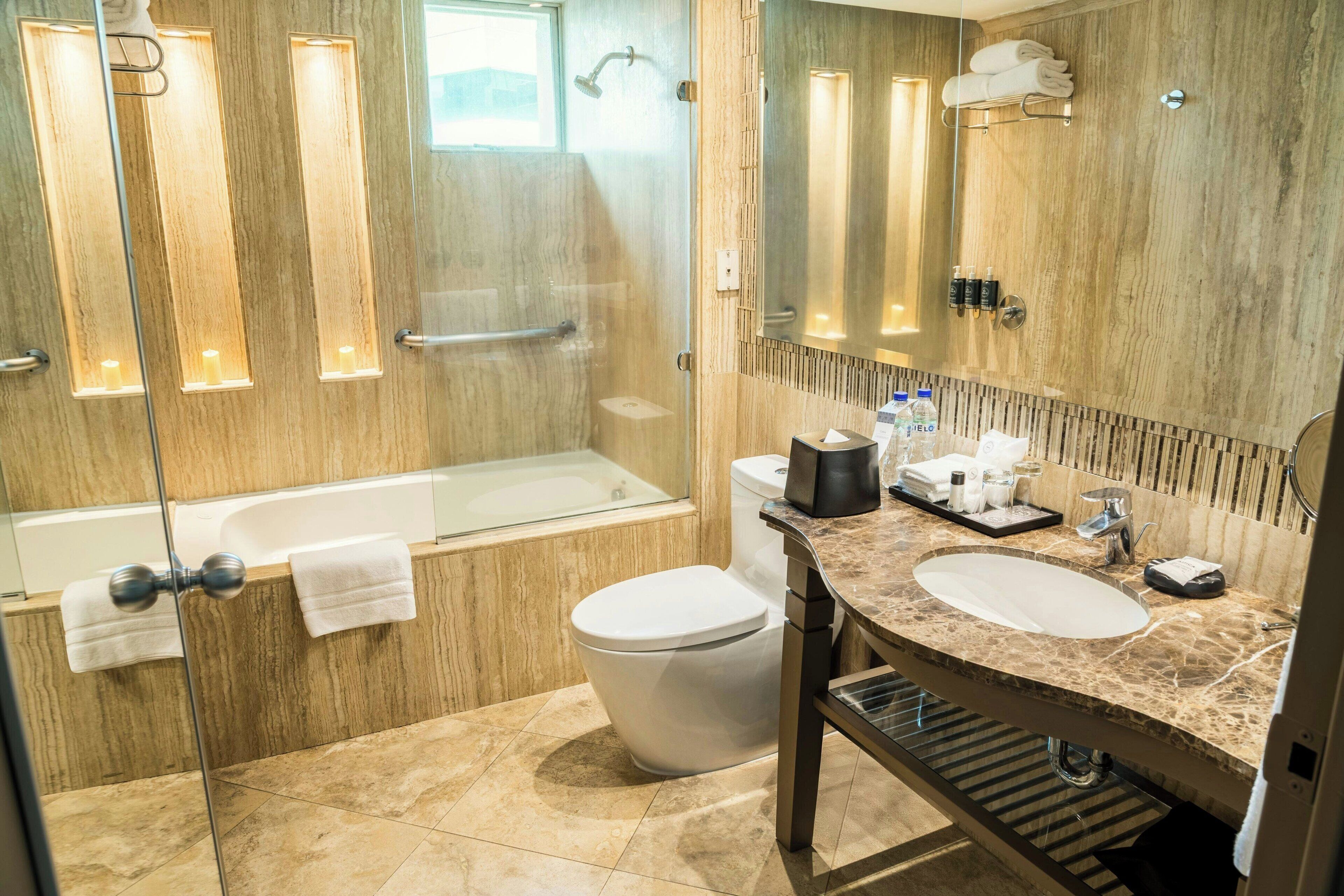 A modern bathroom with a glass-enclosed shower, a bathtub, a toilet, and a vanity with a sink and mirror.