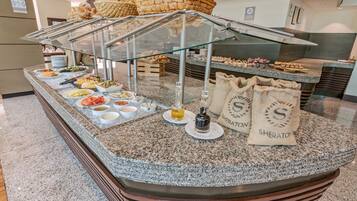 Un mostrador de buffet con diversos alimentos, como pan, pasteles y salsas.