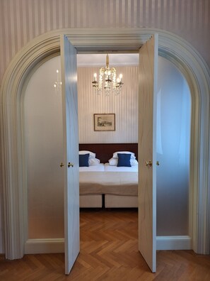 A hotel room with a double bed, a chandelier, and a framed picture on the wall.