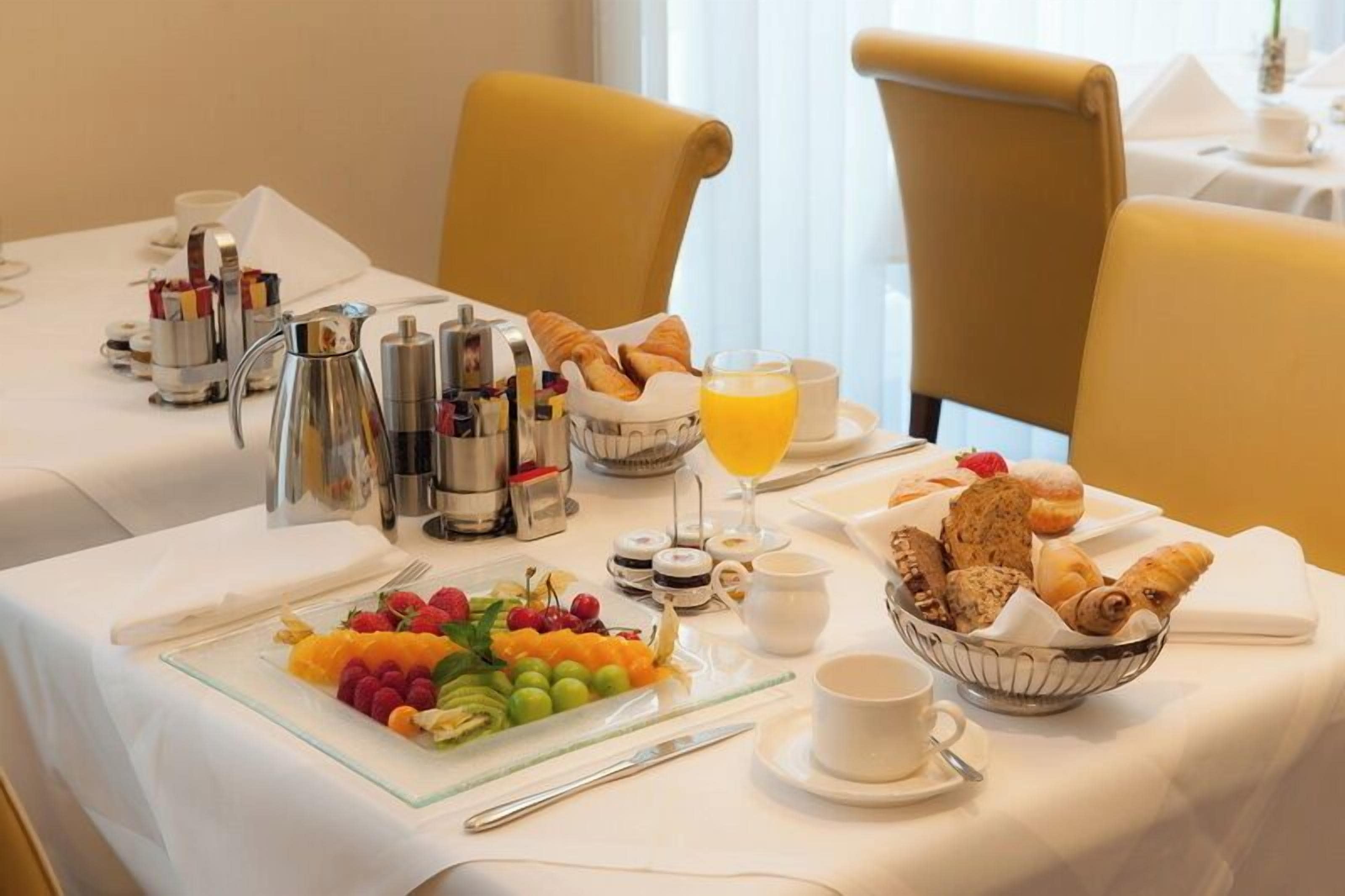 A breakfast setting with a fruit platter, croissants, and coffee.
