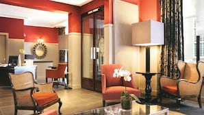 A lobby with a reception desk, seating area, and a large window with curtains. - Crystal Hôtel (Paris)