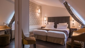 A bedroom with a large bed, two bedside tables, a chair, and a patterned wall. - Crystal Hôtel (Paris)