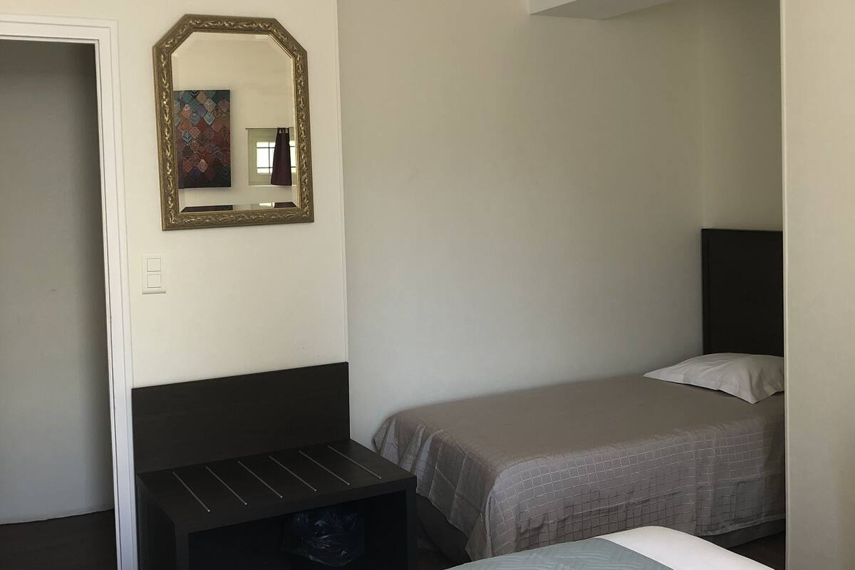 A hotel room with two beds, a dresser, a mirror, and a door.