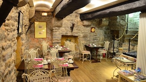 A rustic dining area with stone walls, wooden beams, and wicker chairs. - Hôtel Elizabeth (Saint-Malo)