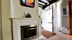 A fireplace with a modern design, a television mounted above it, and a door leading to an outdoor area. - Hôtel Elizabeth (Saint-Malo)
