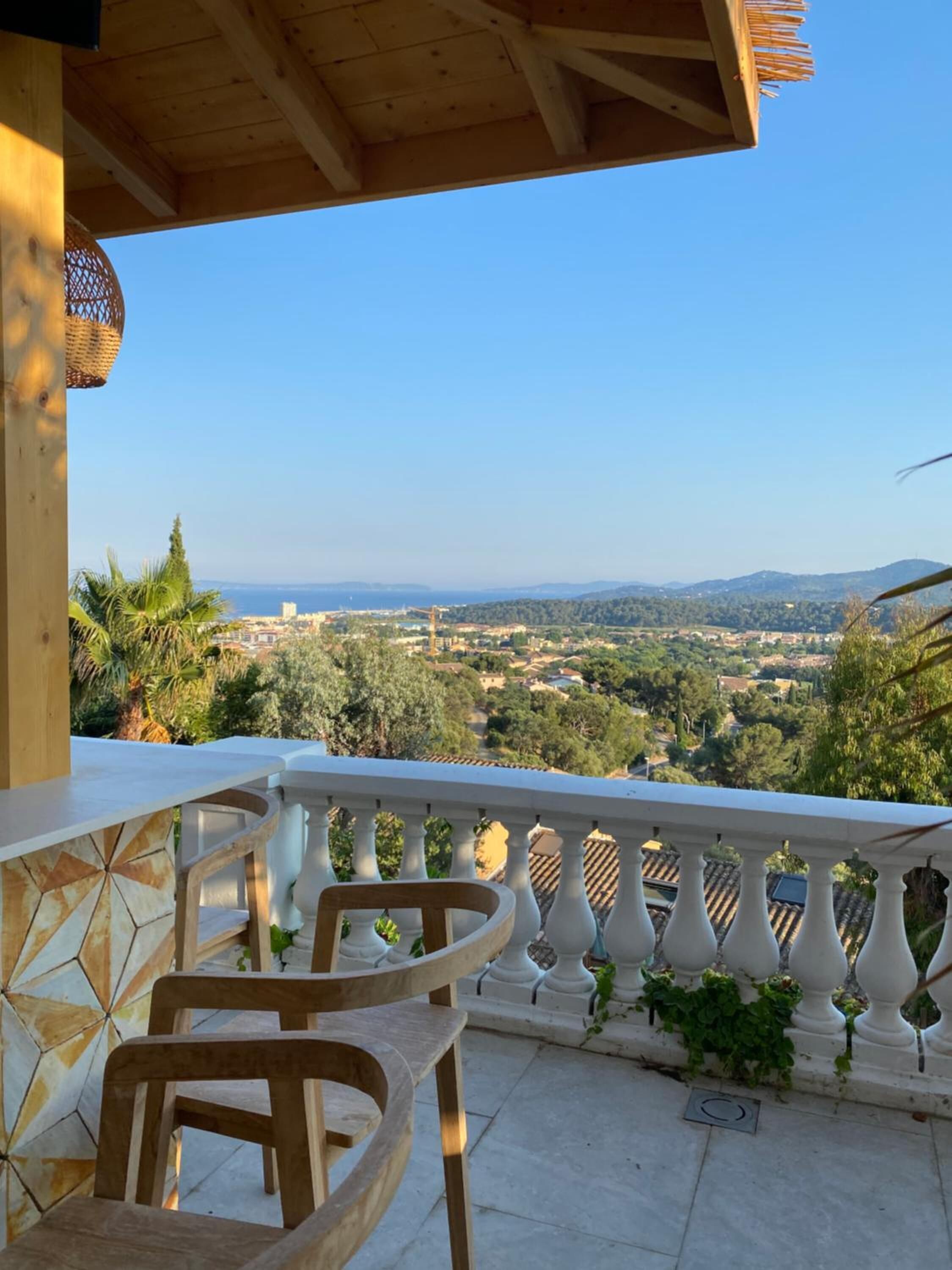 Un balcón con vistas a un paisaje urbano, incluyendo montañas y zonas verdes.