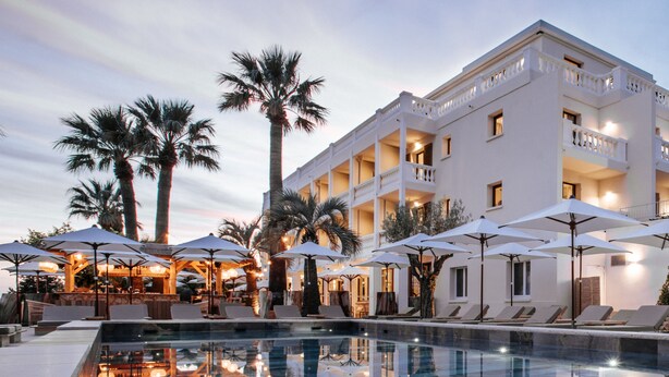 A modern hotel with a pool, palm trees, and outdoor seating areas. - Le Mirage (Bormes-Les-Mimosas)