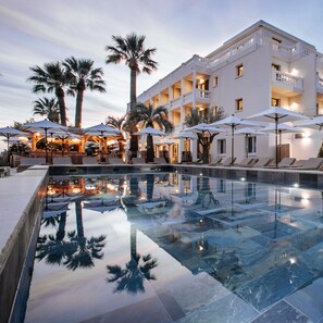 A modern hotel with a pool, palm trees, and outdoor seating areas. - Le Mirage (Bormes-Les-Mimosas)