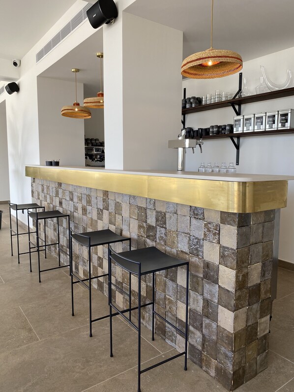 Una cocina moderna con una isla central, taburetes altos negros e iluminación colgante de mimbre.