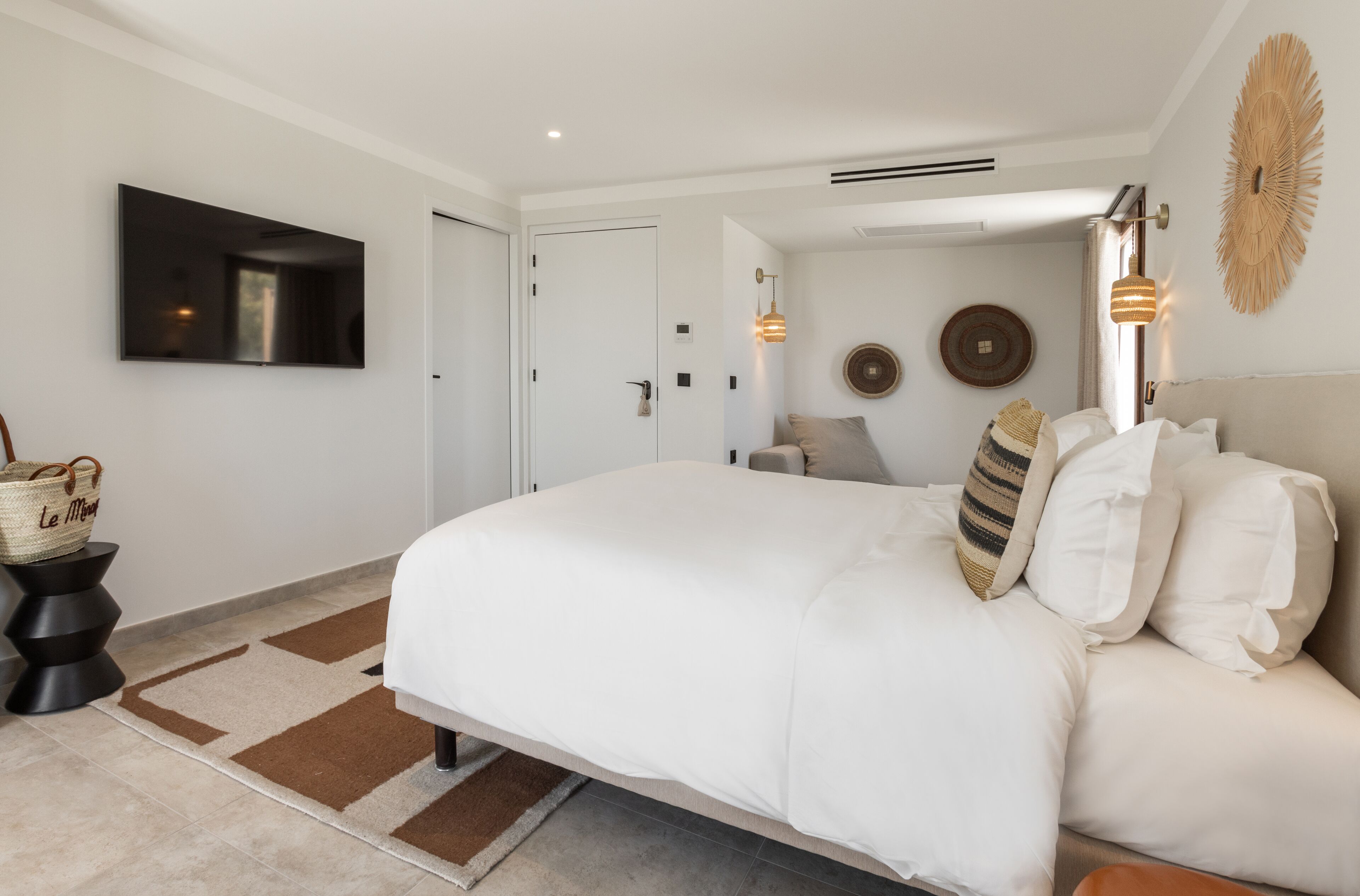 A modern bedroom with a large bed, a flat-screen TV, and a decorative wall piece.