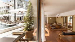 A modern hotel room with a pool, sun loungers, a Pilates studio, and a large window overlooking the pool area. - Le Mirage (Bormes-Les-Mimosas)