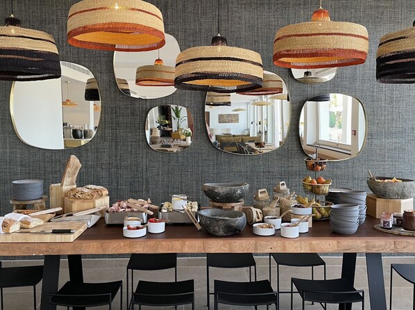 A dining area with a wooden table, black chairs, and various food items. - Le Mirage (Bormes-Les-Mimosas)