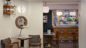 Un espace bar avec des tabourets, un comptoir avec des bouteilles et un mur sur lequel est inscrit le mot « BAR » en grandes lettres.