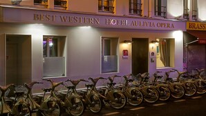 Un hôtel avec une enseigne indiquant « HÔTEL AULIVIA OPERA » et une rangée de vélos devant l’entrée.