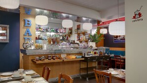 Un restaurant doté d’un bar, de tables, de chaises et de diverses bouteilles et condiments disposés sur des étagères.