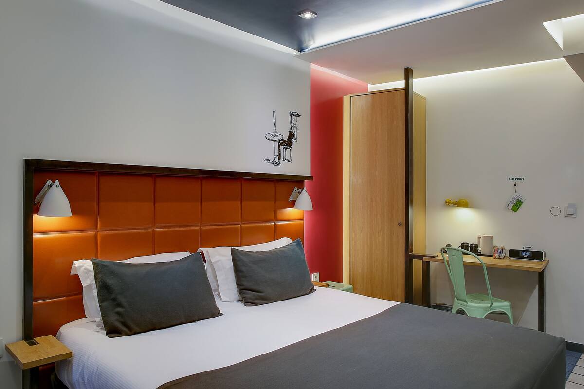 Una habitación de hotel moderna con una cama grande, un escritorio y una silla.