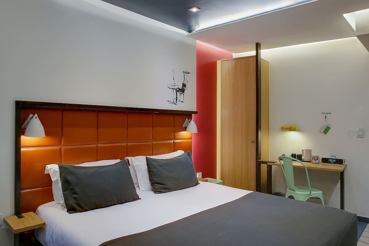 A modern hotel room with a large bed, a desk, and a chair.