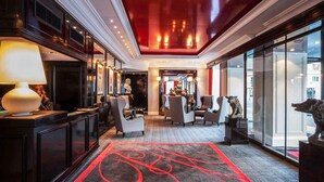 Un vestíbulo de hotel con una recepción, zona de estar y un amplio ventanal.