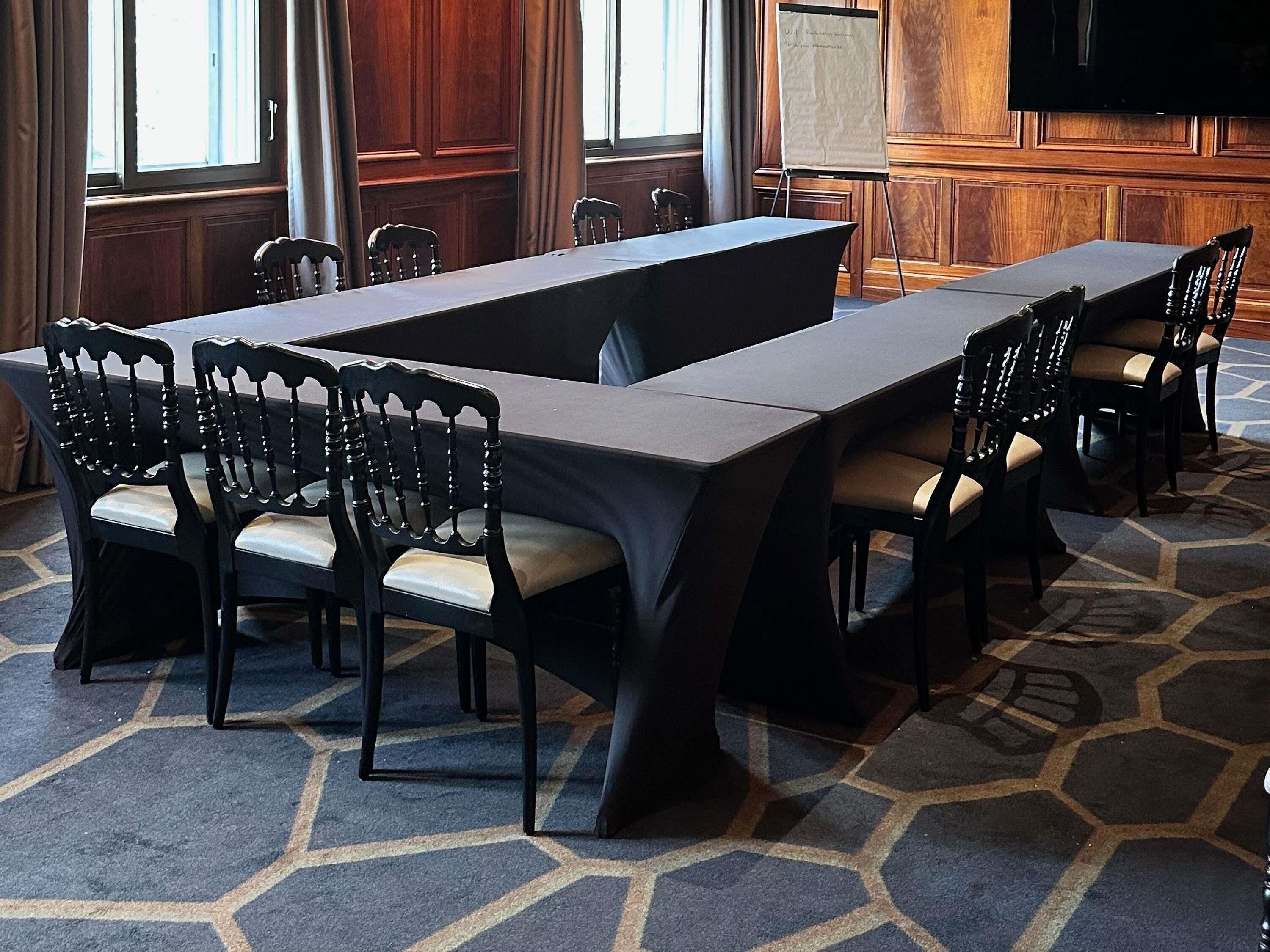 A conference room with a long table, chairs, a whiteboard, and a television.