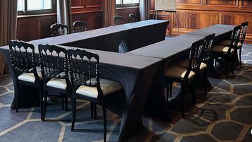 A conference room with a long table, chairs, a whiteboard, and a television.