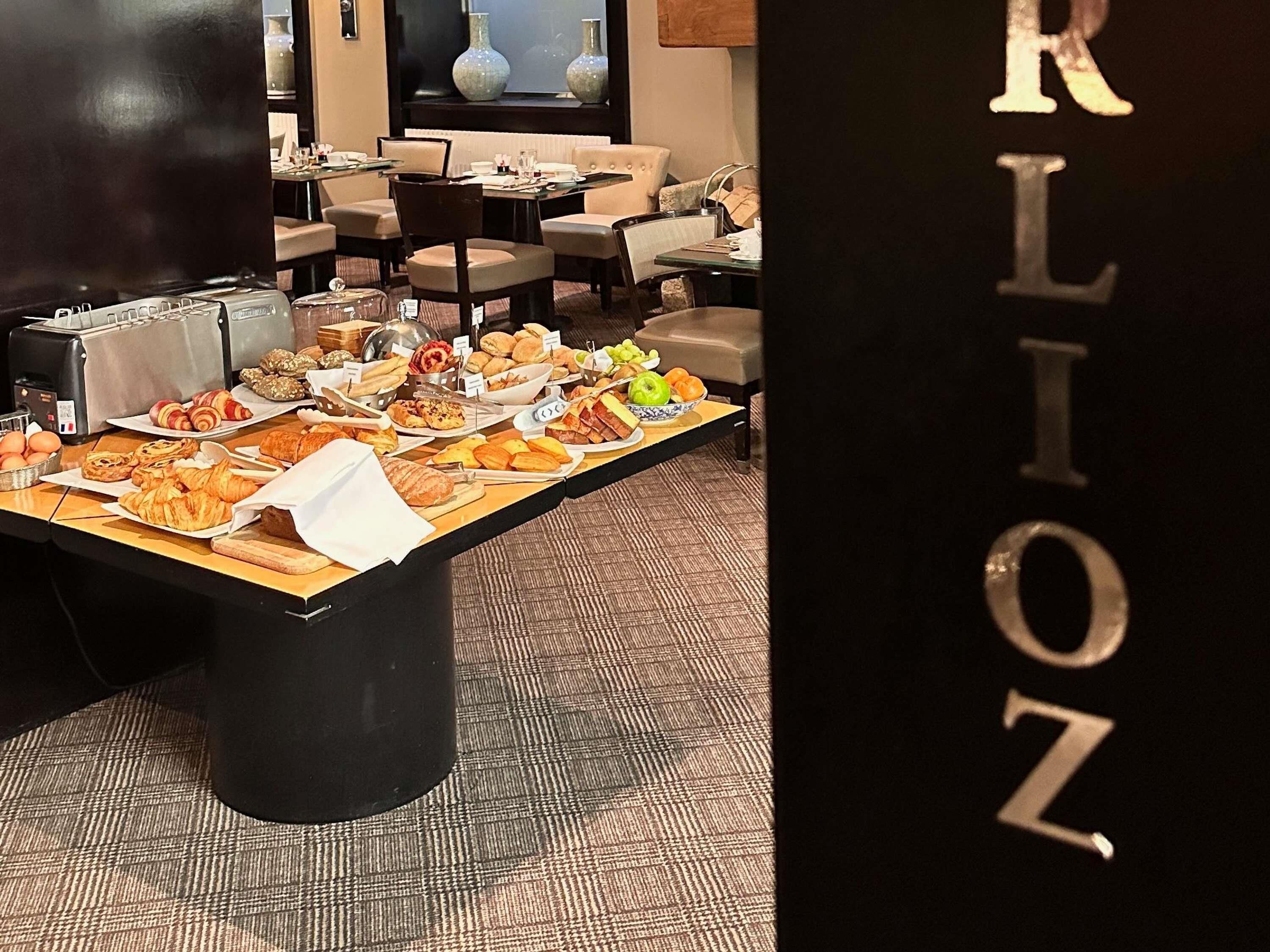 A buffet table with various food items and a seating area with chairs and tables in the background.
