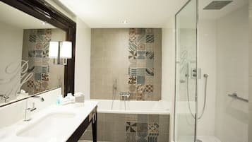 A modern bathroom with a double sink, a glass shower enclosure, and decorative tile patterns on the walls.