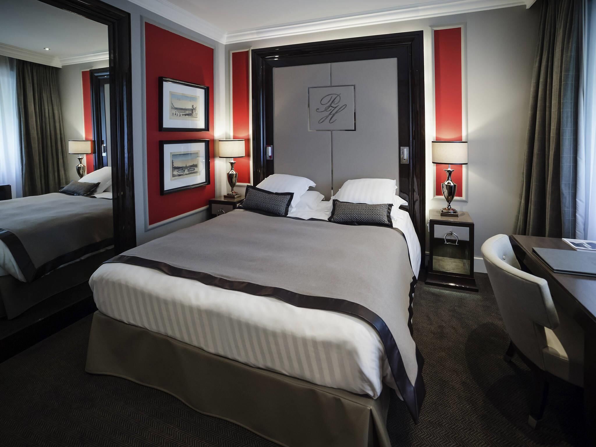 Habitación de hotel con una cama grande, dos mesitas de noche, un escritorio y una silla.