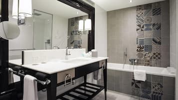 A modern bathroom with a large mirror, a sink, a bathtub, and patterned tiles.