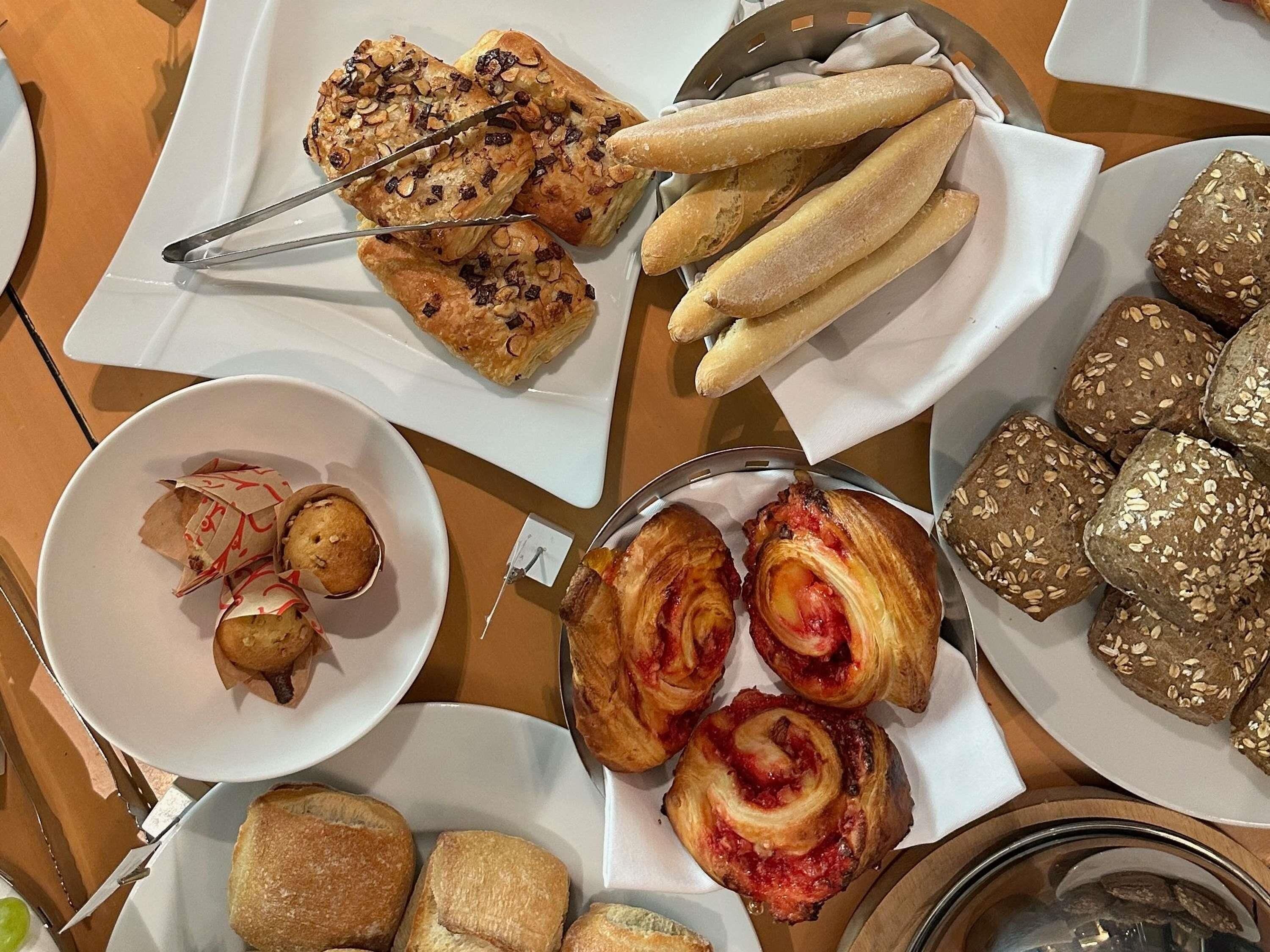 A variety of baked goods including pastries and bread on plates and in a basket.