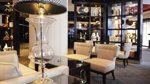 Un vestíbulo con una mesa de centro de vidrio, una lámpara decorativa y una zona de estar con sillones y sofás.