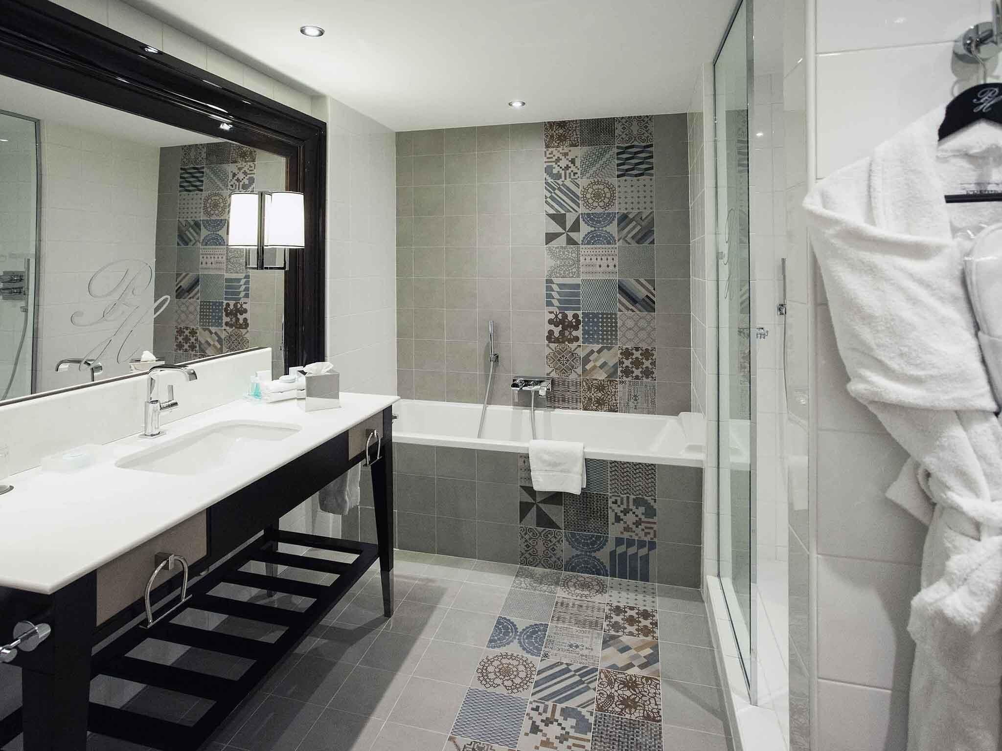 A modern bathroom with a double sink, a large mirror, a bathtub, and a glass shower enclosure.