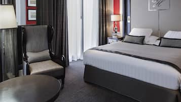 Ett hotellrum med en säng, en stol, ett bord, en lampa och en skylt som är upphängd på väggen.