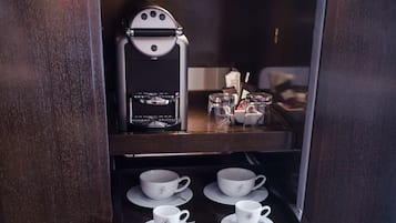 A wooden cabinet with a coffee machine, cups, and saucers.