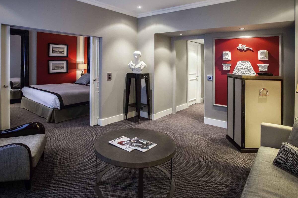 Une chambre d’hôtel comprenant un lit, un bureau, une chaise, une table ronde et un petit réfrigérateur.