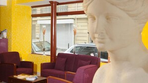 Une pièce avec un mur jaune, une grande fenêtre et une statue au premier plan.