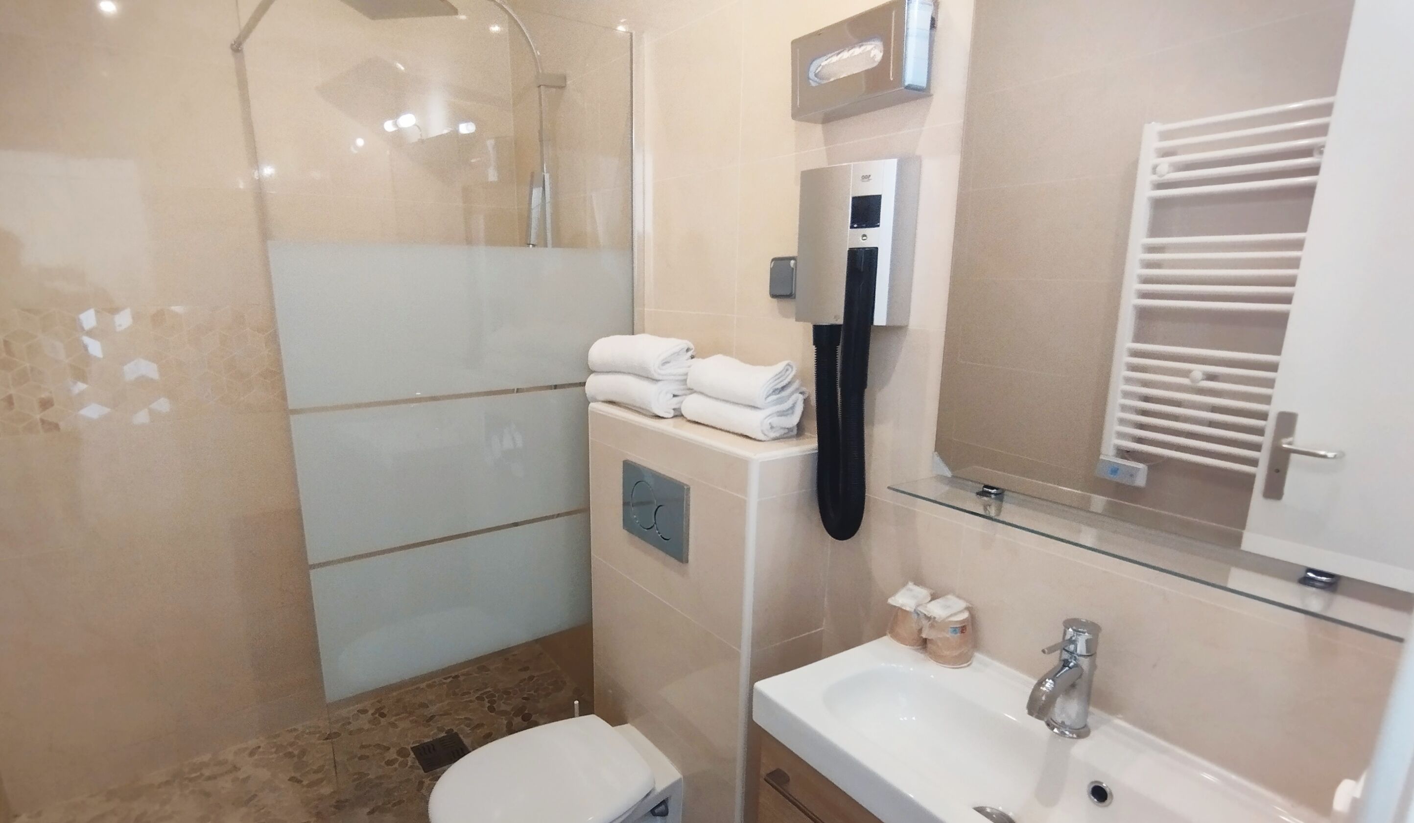 A bathroom with a shower, toilet, sink, and towel rack.